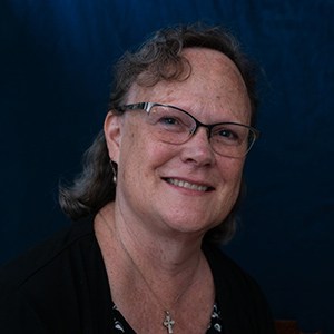 Monsignor Bernie Schmidt gives a blessing at the altar, with candles surrounding him.