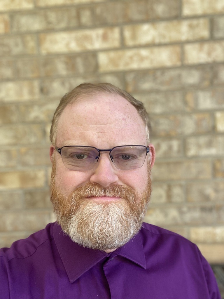Monsignor Bernie Schmidt gives a blessing at the altar, surrounded by candles and a gathering.