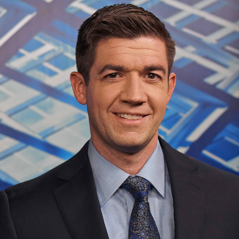 Monsignor Bernie Schmidt gives a blessing at the altar, with candles surrounding him.
