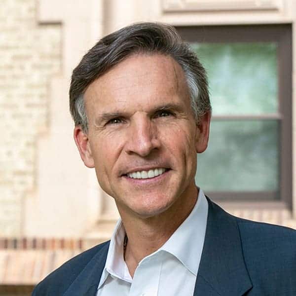 Monsignor Bernie Schmidt gives a blessing at the altar, surrounded by candles and a gathering.
