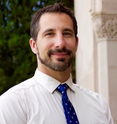Monsignor Bernie Schmidt gives a blessing at the altar, with candles surrounding him.