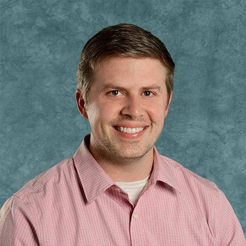 Monsignor Bernie Schmidt gives a blessing at the altar, surrounded by candles and a gathering.