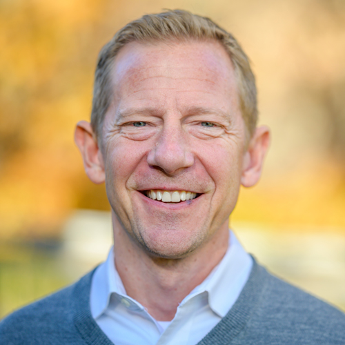 Monsignor Bernie Schmidt gives a blessing at the altar, surrounded by candles and a gathering.