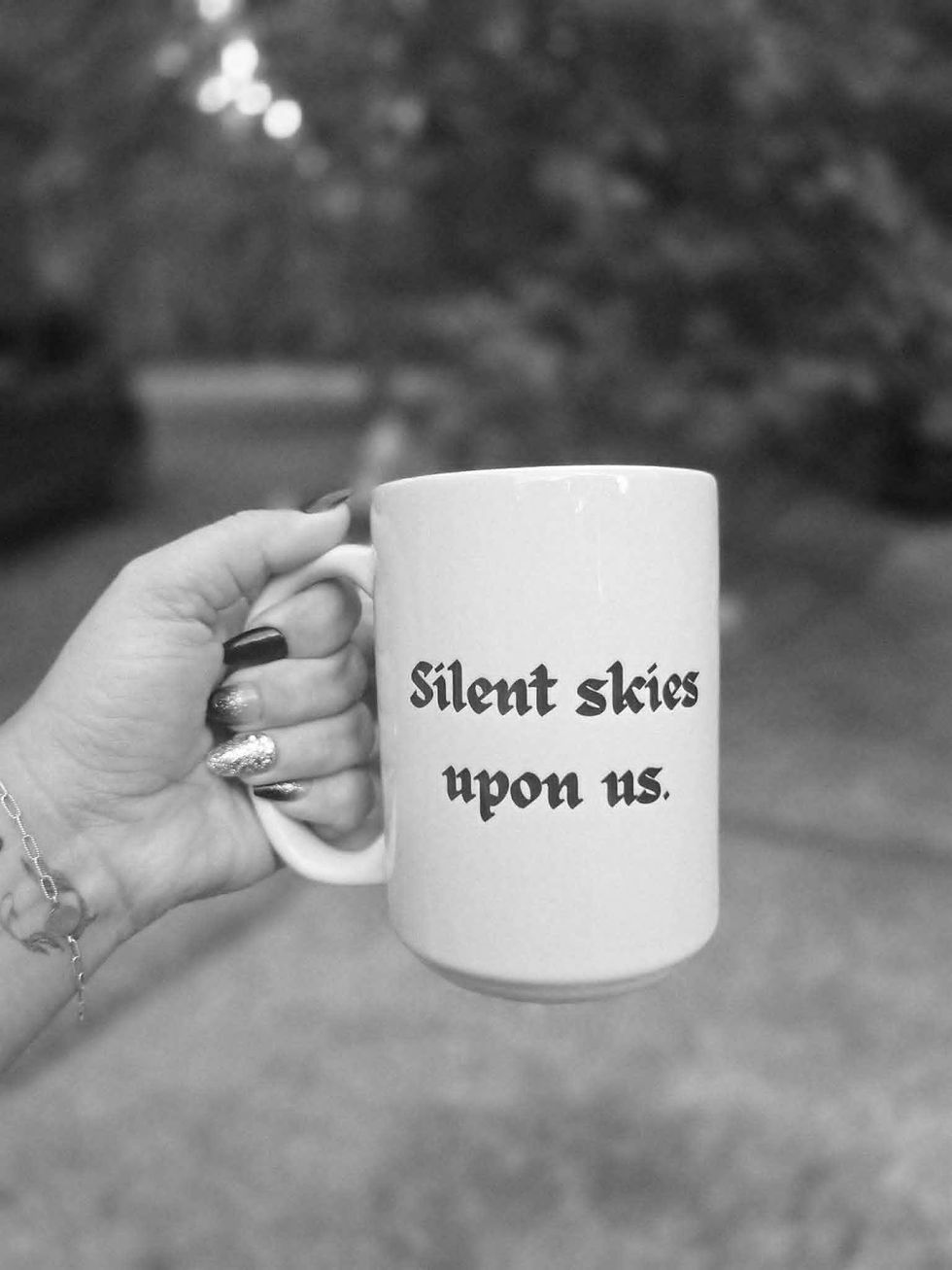 Hand holding white mug with text Silent skies upon us.