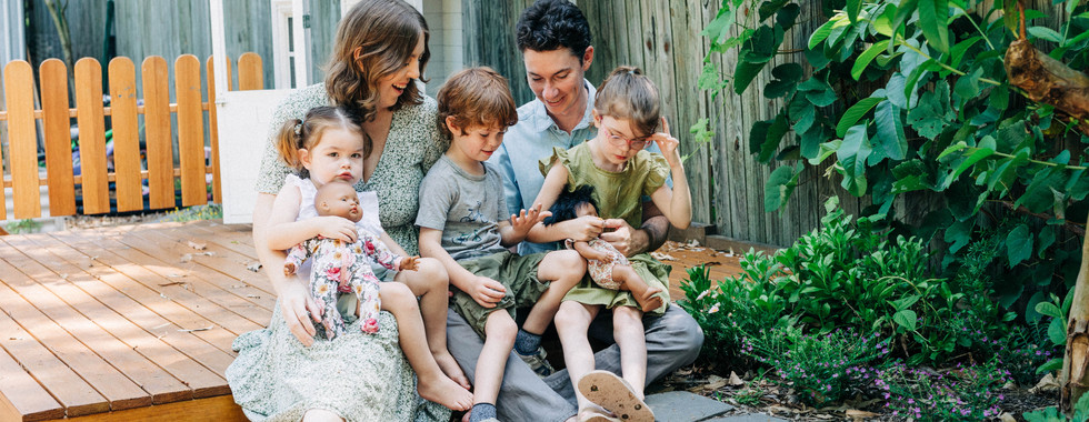 a family sitting together laughing during their photoshoot in their backyard