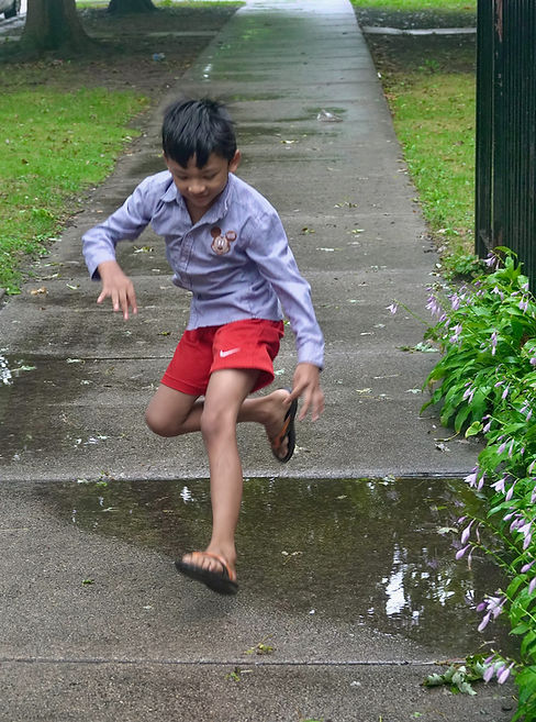 Nurshafidah's brother, Hamza, jumps over a puddle