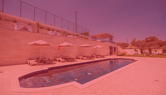 A daytime view of the swimming pool with a striking red filter, creating a bold, surreal atmosphere that contrasts with the natural surroundings.