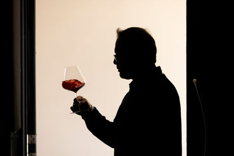 Waiter silhouetted holding red wine