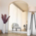 Large gold arch mirror in modern living room with chair and soft curtains, elegant tall arched wall mirror UK design