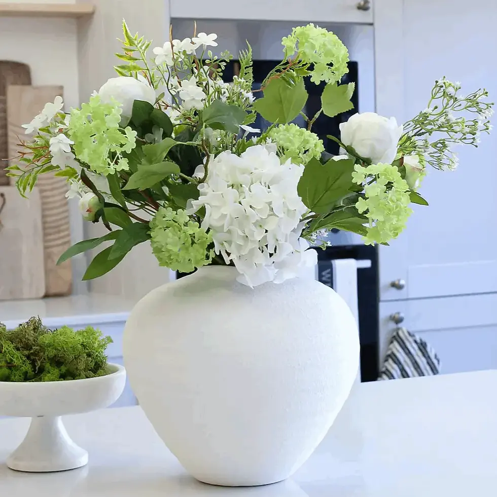 Thumbnail: White ceramic vase with green and white flowers on a table, adding natural luxury to a bright modern room.