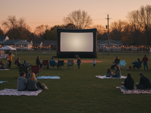 A large movie screen in the outfield of a community park, guests gathered on blankets