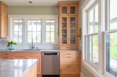 Bright kitchen with natural wood cabinets, stainless steel range, white subway tile, and a large central island with a thick, veined marble countertop. Designed by Apex Kitchens and Baths in Middletown Rhode Island