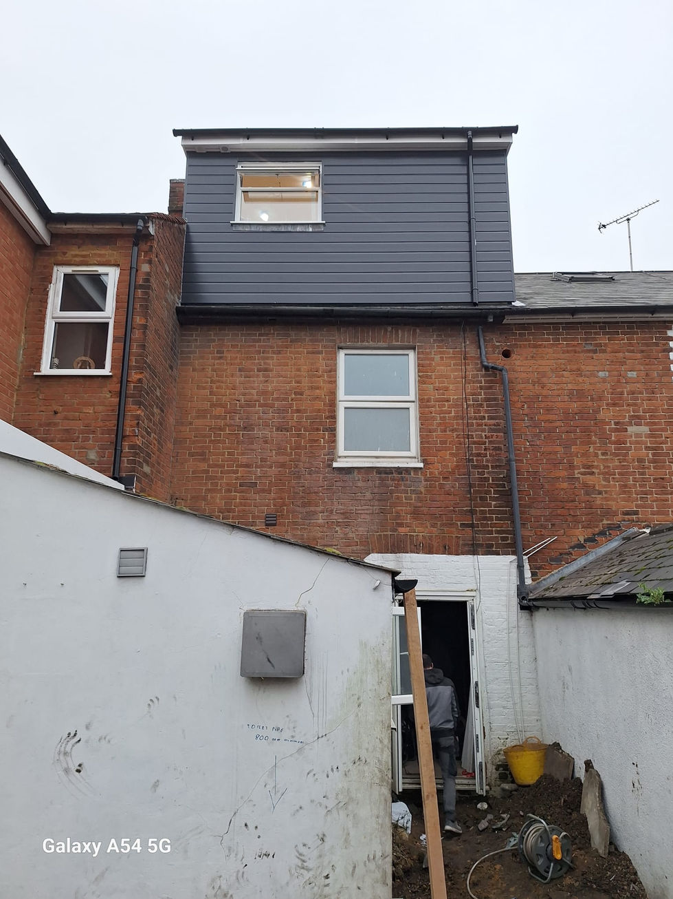 Close up of dormer side wall with dark cladding, window detail and rainwater pipe