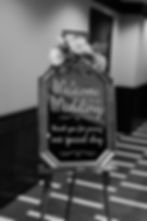 A sign that reads "Welcome to our Wedding" placed on an easel, decorated with fresh flowers.