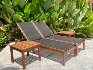 wooden lounge chair against lush tropical plant background with two wood side tables square
