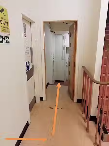 An arrow pointing along a corridor towards a stairwell.