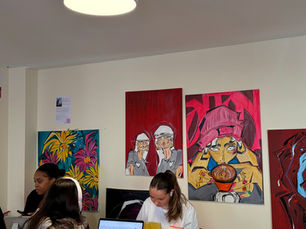 Espace café coworking à Toulouse avec clients en train de travailler entourés de peintures colorées lors d’une exposition d’art locale.