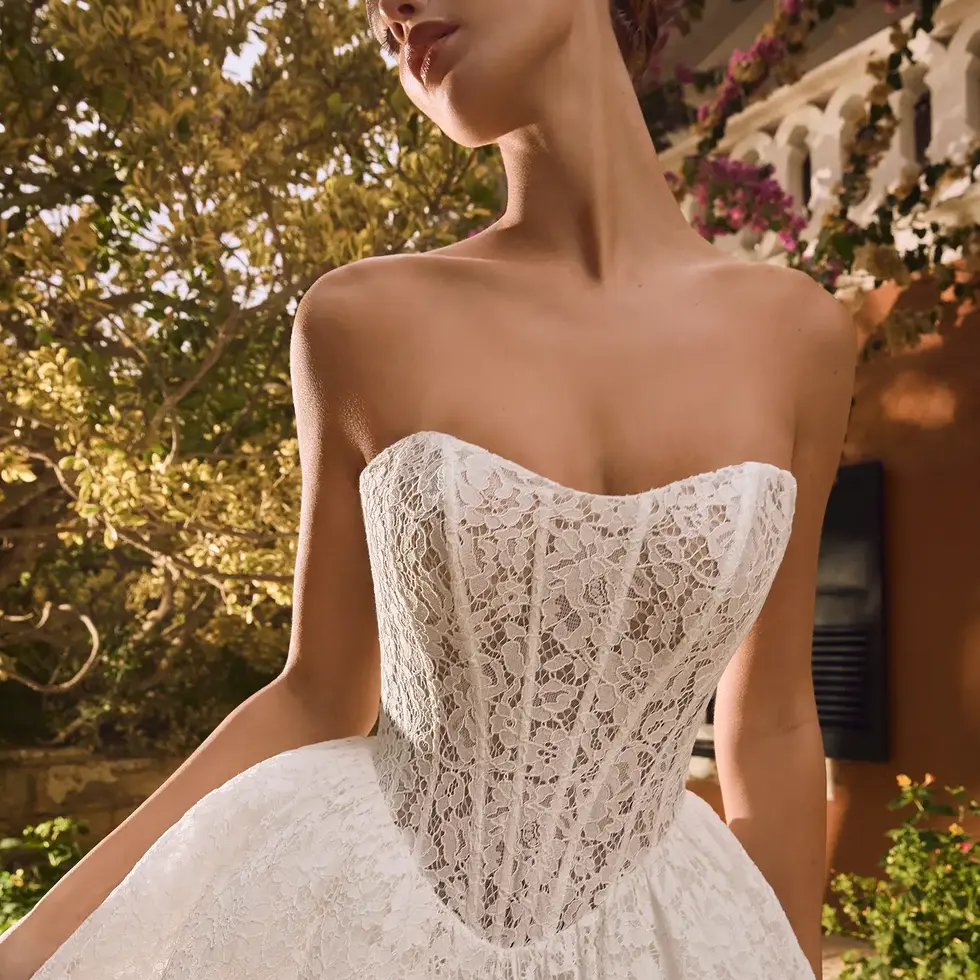 Sposa con abito bianco senza spalline, Sposami Atelier, sullo sfondo verde.