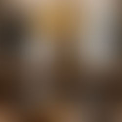 Chic bar with empty stools, ornate white chandelier, and bottles lined up. Marble floor, modern decor, large windows in the background.