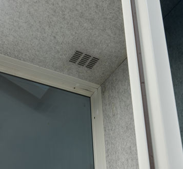 Close-up of the integrated silent air exchange system and recessed LED lighting in the acoustic ceiling.