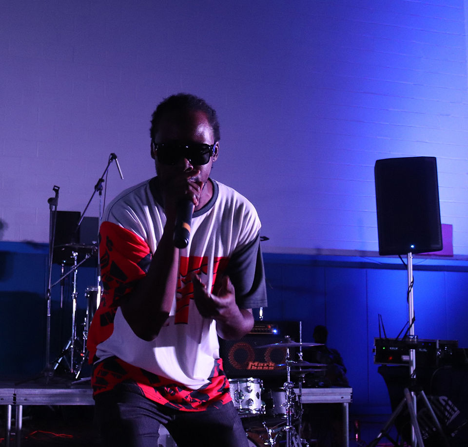Man with sunglasses on stage singing into microphone with BGCCA.