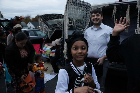 Group of people smiling near a car with decorations and a young girl smiling.