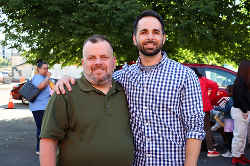 Two men smiling and posing, one arm over the other's shoulder.