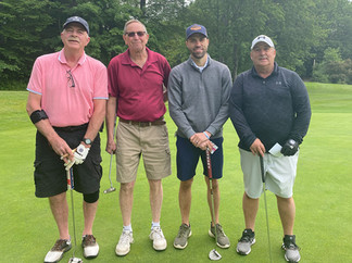 Four golfers stand together on a golf course with their golf clubs, 2025 Golf Tournament.