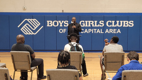 Man speaking in front of Boys & Girls Club of Capital Area crowd. BGCCA.
