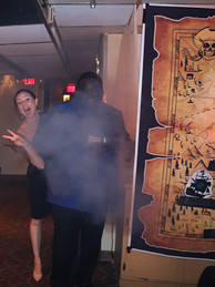 Woman smiling, making peace sign near man and pirate map, 2022 Gala: Pirate Cruise, BGCCA.