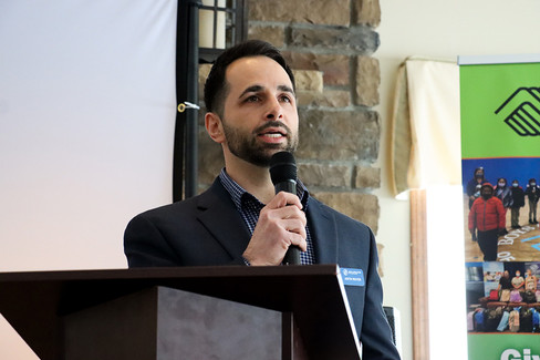 Man speaking into microphone at podium; professional event background