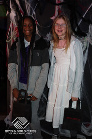 Two friends smile, holding bags during BGCCA's Halloween celebrations in 2023.