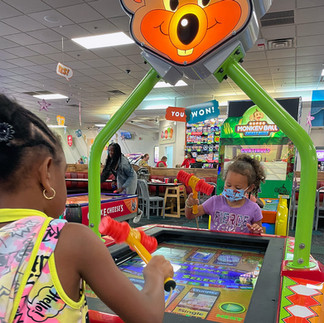 Two young girls playing arcade games at Chuck E. Cheese during a fun day out.