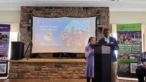 Speakers at 2024 Donor Breakfast by the projector with visible text