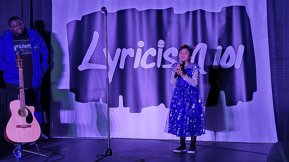 Young girl singing on stage, Lyricism 101 background, holding microphone.