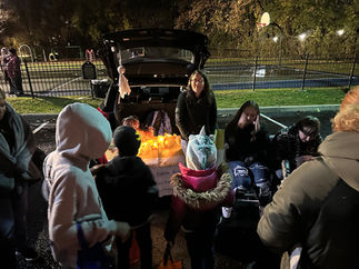 Children and adults at a Halloween event with pumpkins and trunk or treat.