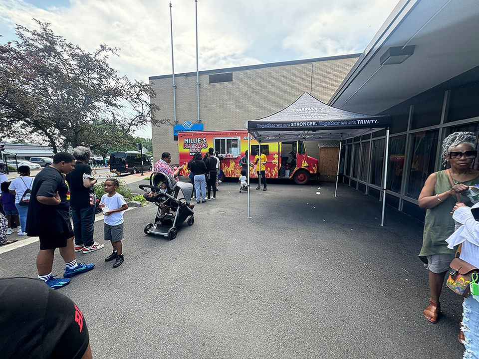People gathered near a food truck at an outdoor event to eat and socialize.