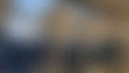 Two decorative paper snowflakes hanging in front of a window frame BGCCA