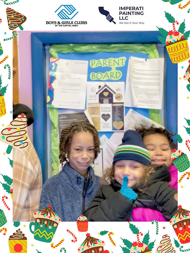 Three young children smiling in front of a Parent Board, BGCCA.