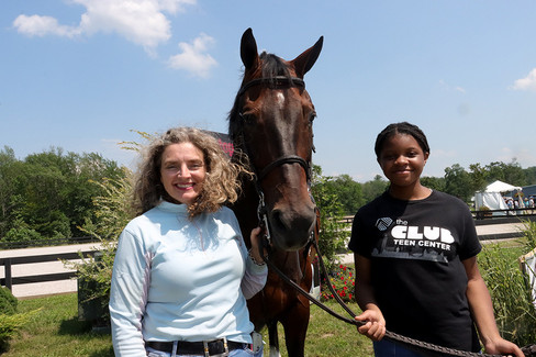 Woman and girl pose with a horse under a clear blue sky BGCCA
