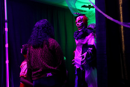 Clown figure in a spooky room, people in front, Halloween event BGCCA.