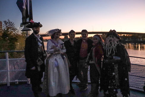 Group of pirates posing, 2022 Gala: Pirate Cruise, on a boat at sunset.