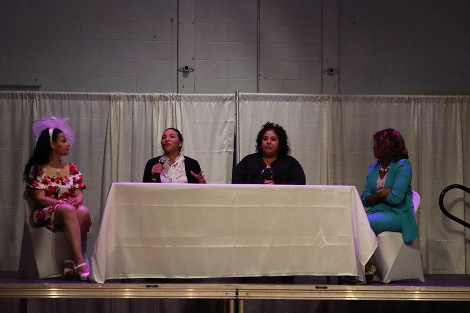 Panel of women at table speaking in front of BGCCA's backdrop.