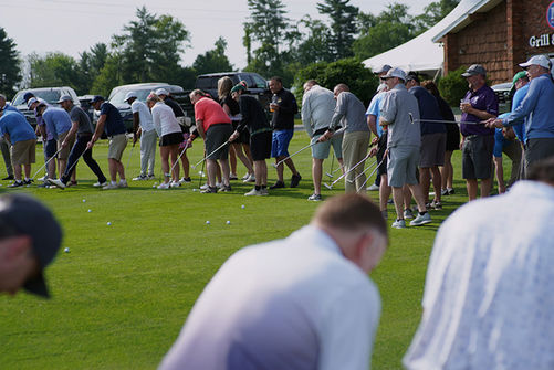 Group of golfers practicing on the green during the 2025 Golf Tournament.