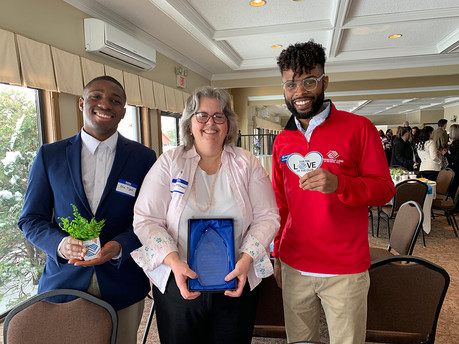 Group of three smiling people holding awards and plants. BGCCA event.