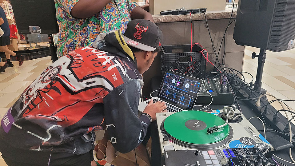 DJ mixing music with laptop and record player, event setting, BGCCA.