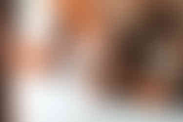 Two women sit at table, one writing, and the other looking off. BGCCA