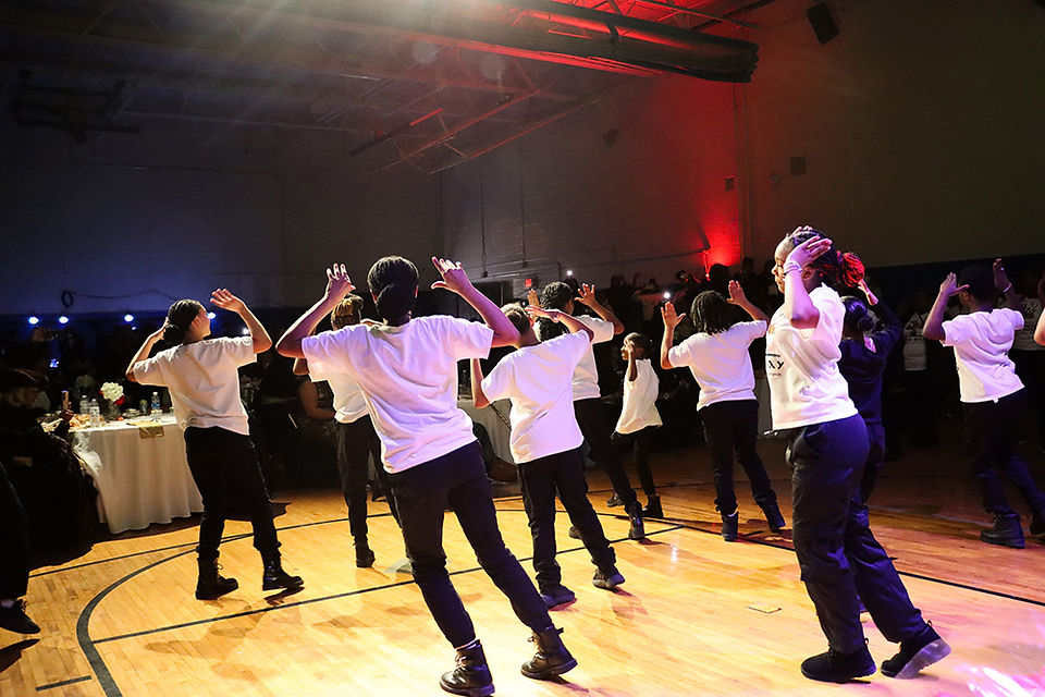 Group of students dancing during a school event with raised arms, BGCCA
