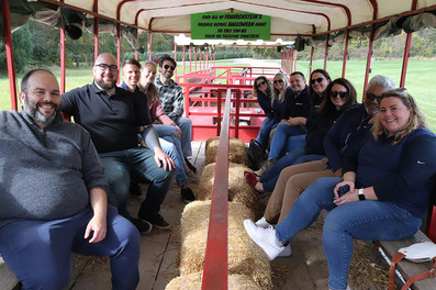 Group of people riding a hayride, with visible text on banner BGCCA.