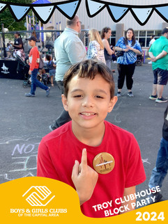 Smiling boy with a red shirt and button, people, and background scene.